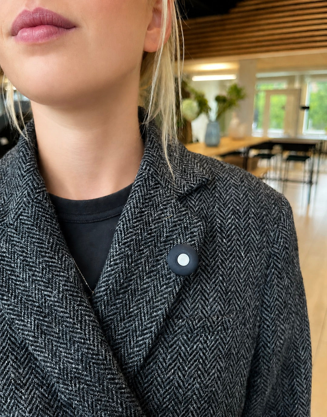 Button PRO clipped to the lapel of a wool coat, worn indoors