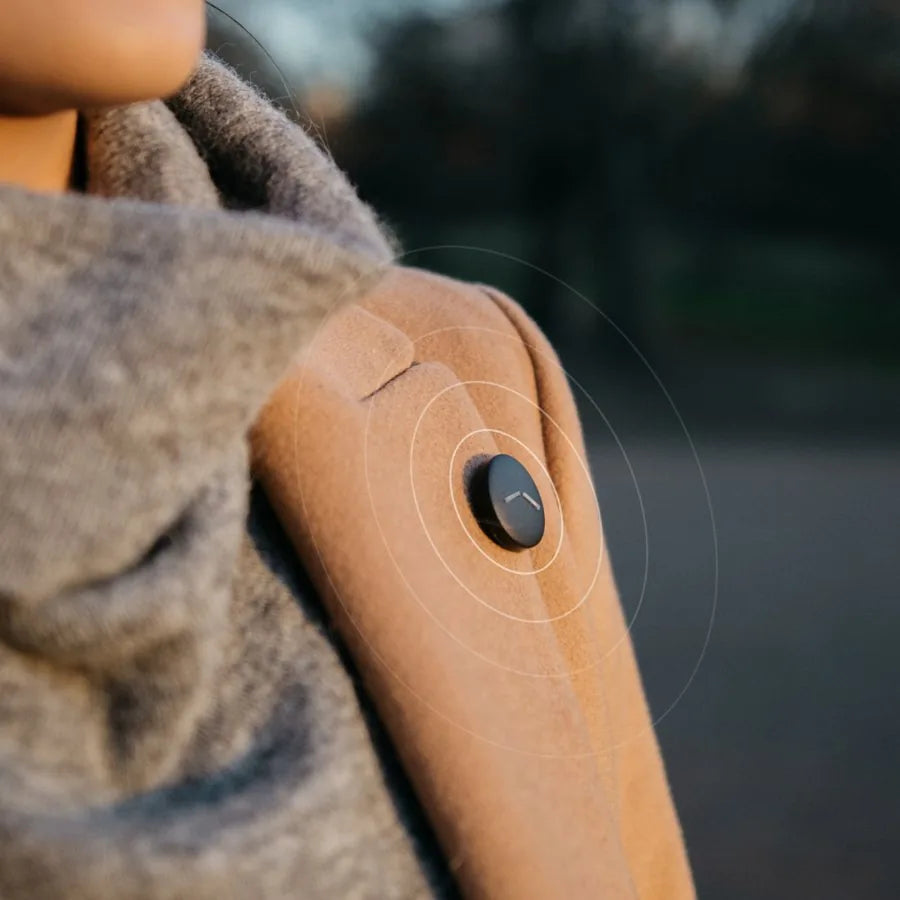 Button V1 clipped to the lapel of a coat, worn outdoors